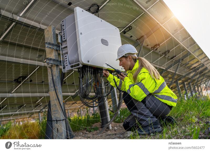 Technician with walkie-talkie checking a distribution box at a solar field. Alternative energy ecological concept image. master engineer modern technology plant