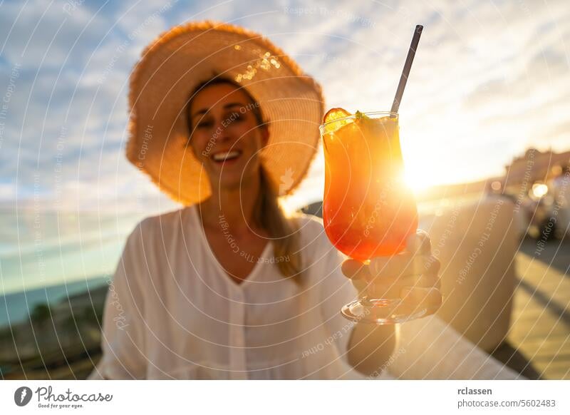 Smiling woman in straw hat holding a cocktail against a sunset backdrop paradise beach playa coastline tropical canary island hotel smiling woman vacation