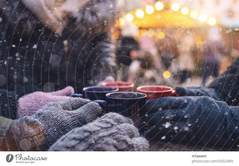 Hands in gloves warming up around steaming mugs of mulled wine at a christmas market, with copyspace for your individual text. punch copy space advent german
