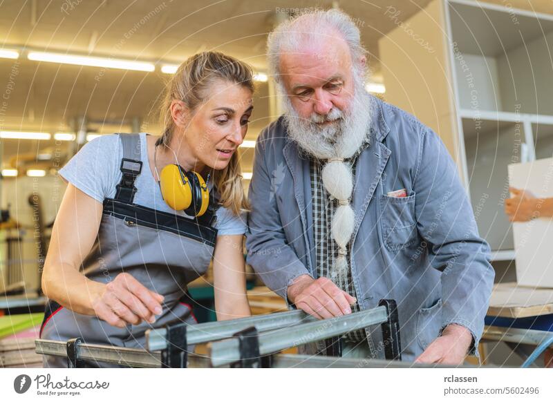 Carpentry master and apprentice focused on clamping wood in a workshop professional craftsman workbench furniture industry worker wooden timber carpentry