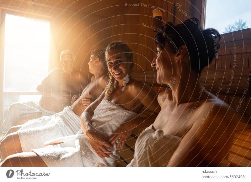 People relaxing and sweating in hot sauna wrapped in towel. Interior of Finnish sauna, classic wooden sauna with hot steam. Russian bathroom. Relax in hot bathhouse with steam.
