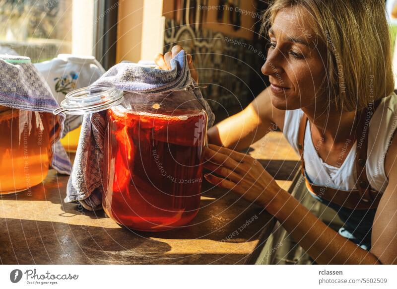 Happy Woman examined kombucha tee with mushroom layers in a large jar. organic healthy drink fermented food, Probiotic nutrition drink for good balance digestive system.