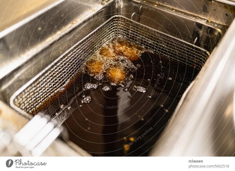 fried potato balls deep frying in deep frying fat at a commercial kitchen of a restaurant. Luxury hotel cooking concept image. delicious food styling