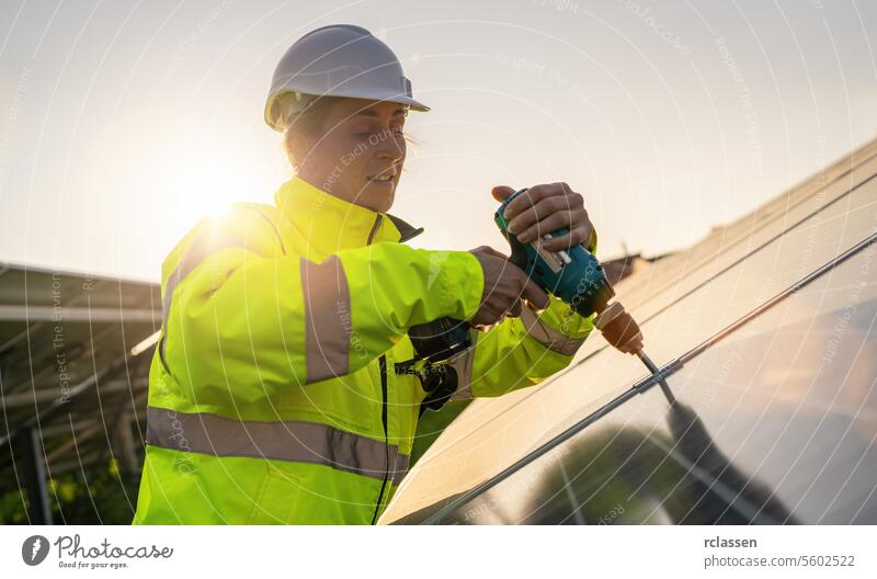 Technician assembling solar panels with a cordless drill at sunset. Alternative energy ecological concept image. master engineer technology plant industry
