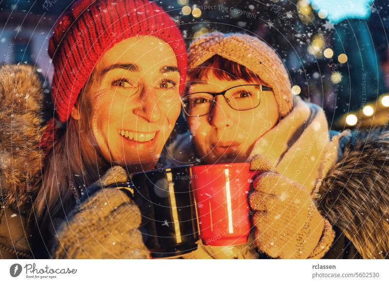 friends drinking hot mulled wine or punch at a Christmas market merry christmas cup hot chocolate gloves traditional christmas market advent german snowflakes