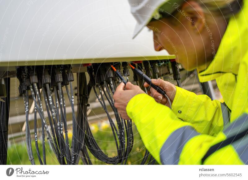 Technician using a voltage tester on a solar field's electrical distribution box. Alternative energy ecological concept image. technology plant industry