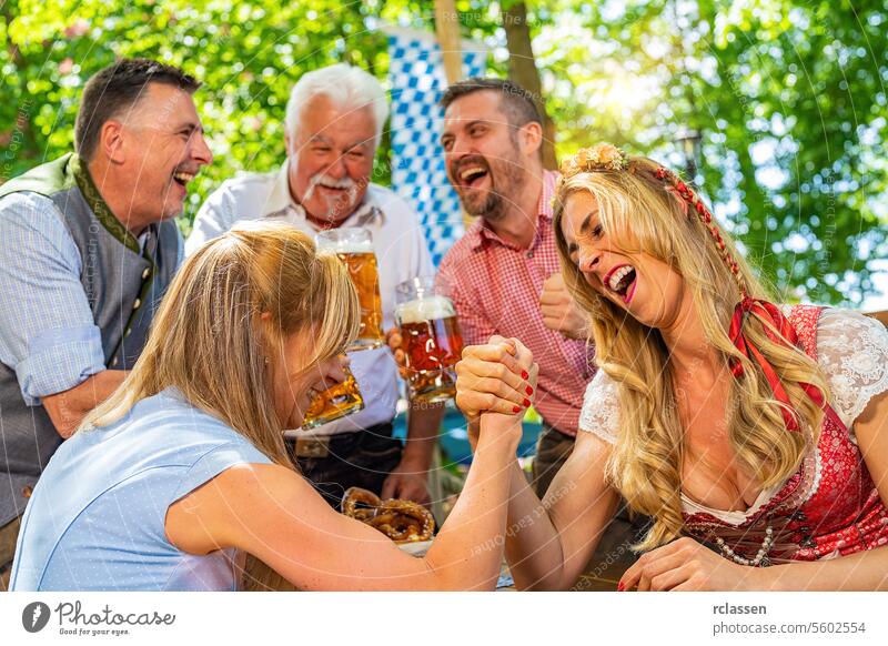 Bavarian friends practicing the high art of arm wrestling in a beer garden gambling cheer on pretzels game woman grandfather senior flag group hands bavarian