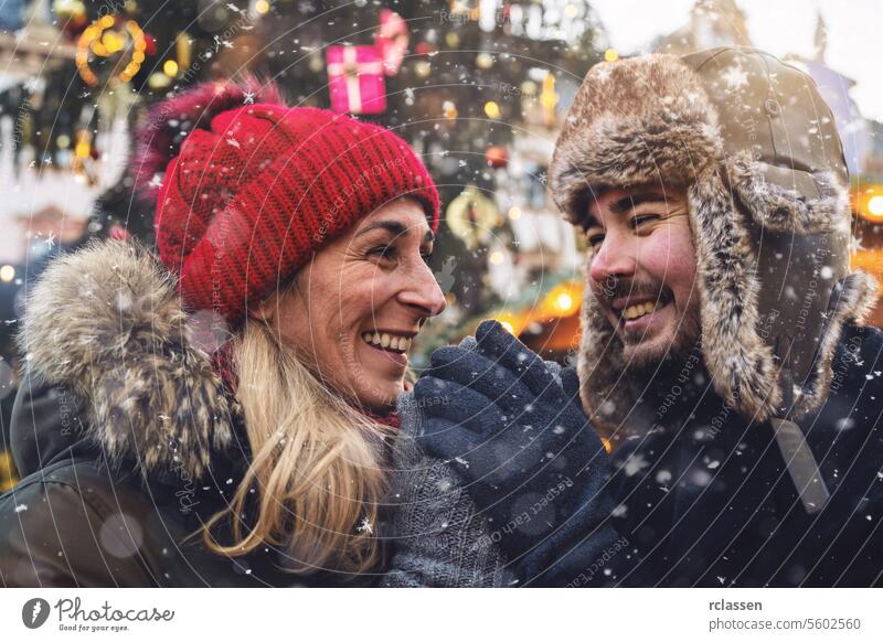 couple shares a warm moment as they hold hands, with a festive Christmas market in the background friends mulled wine boyfriend beard tourism dating fair travel
