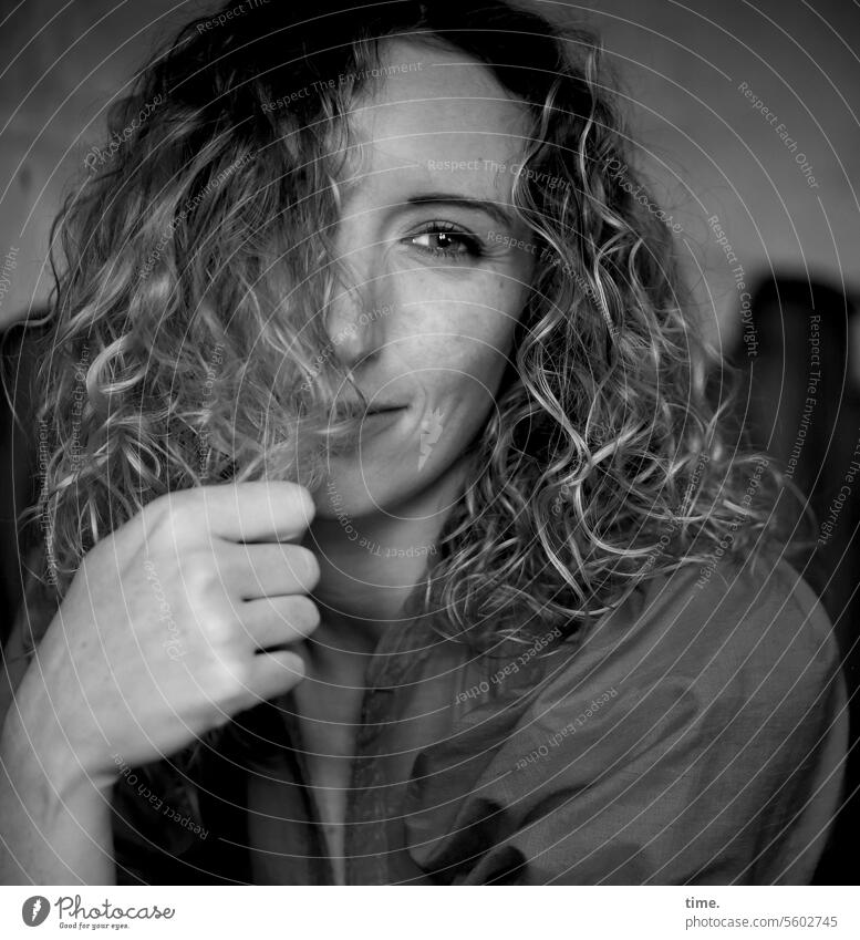 Woman with curly hair portrait feminine block Hairdresser Hand Dress Smiling gentle kind Trust Impish amused Protection One-eyed Dim Laughter lines