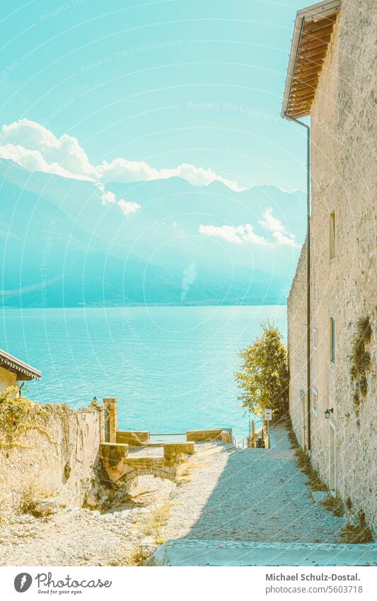 Picturesque view past quarry stone buildings to Lake Garda and Monte Baldo Lago Italy Lombardy Water Harbour seascape port picturesque lake view pastel ugly