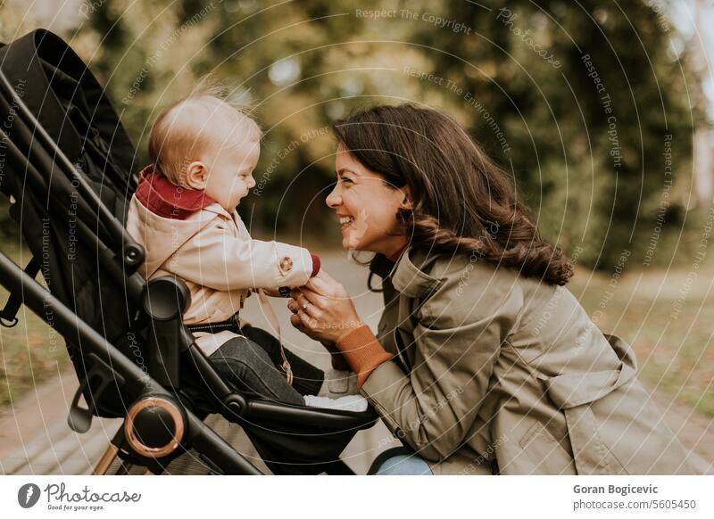 Young woman holding cute baby girl in the autumn park small caucasian mother outside daughter child little love happiness together family play mom smile season