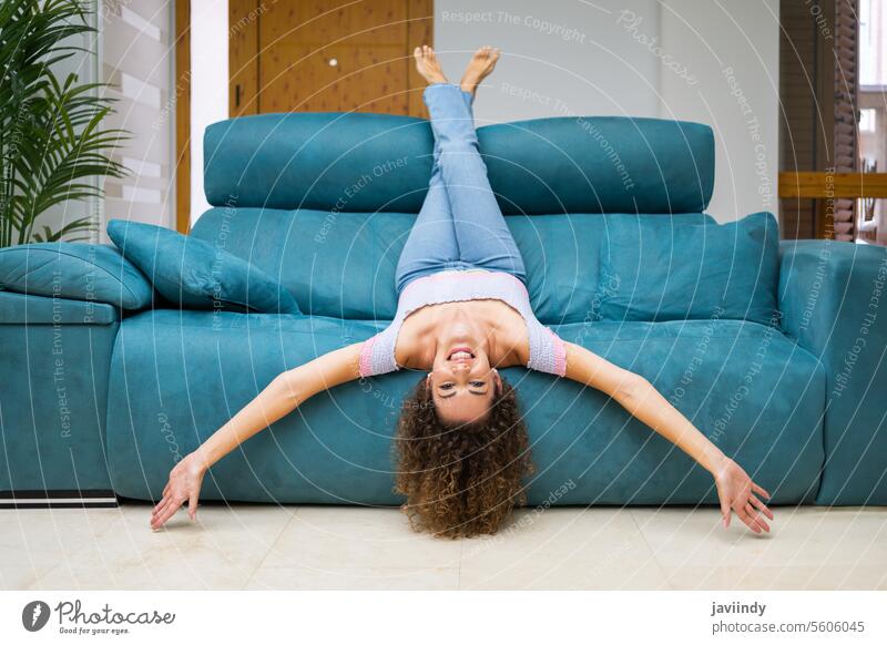 Happy woman woman lying upside down on couch at home smile having fun sofa barefoot curly hair chill happy comfort pleasure positive glad laugh content optimist