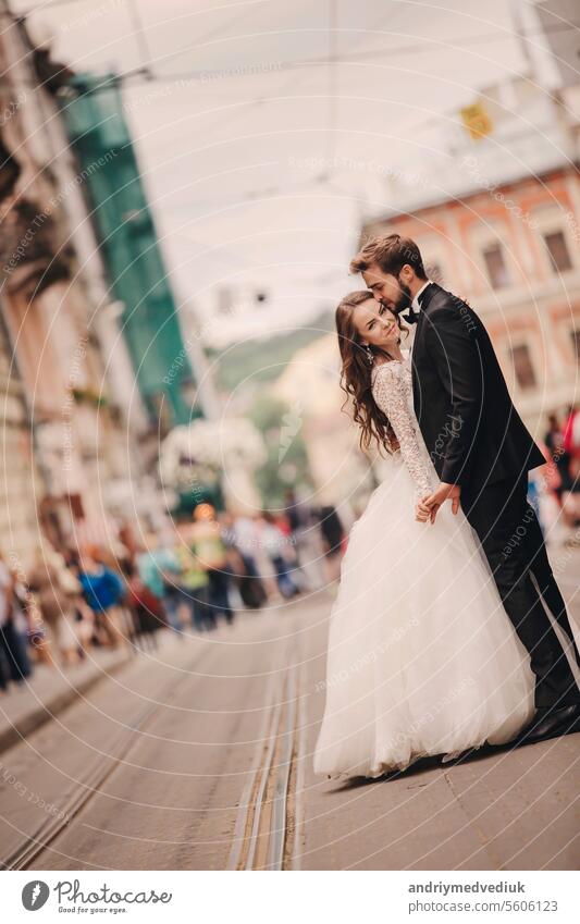 Happy newlyweds couple on a walk in old European town street, gorgeous bride in white wedding dress together with handsome groom. happy european love city woman
