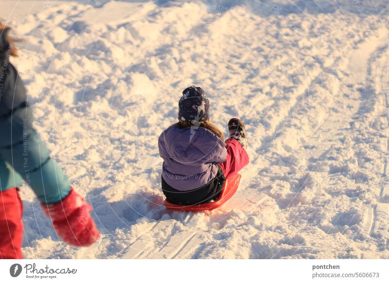 two children sledging, tobogganing. Bobsleigh Zipfelbob Snow Winter Children's game fun winter clothes variegated Gloves watch Cold White Exterior shot