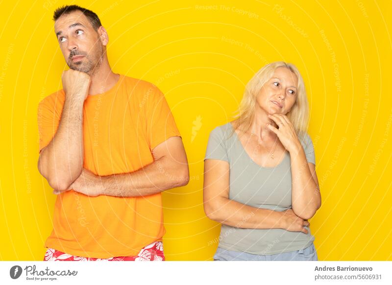 Contemplation of two lovers caucasian 40s couple spouses wife and husband boyfriend and girlfriend looking upwards, planning for future, thoughtful and pensive people isolated in yellow