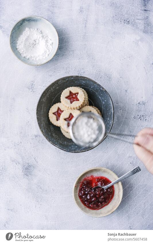 A woman sprinkles powdered sugar over shortbread cookies. Top view. Christmas & Advent biscuits Confectioner`s sugar Dessert plan Christmas biscuit Baking