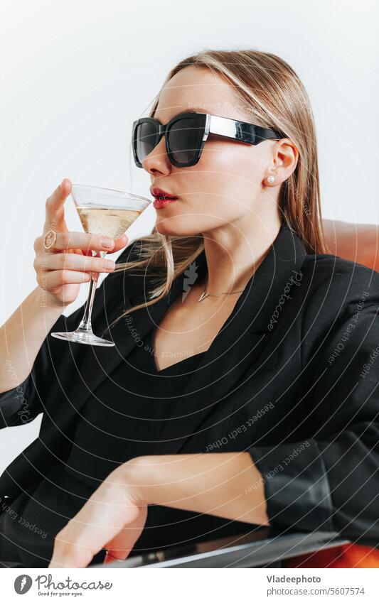 Lady boss in total black look sitting in armchair and drink wine, weekend young woman martini fashion style suit jacket independent model person beverage