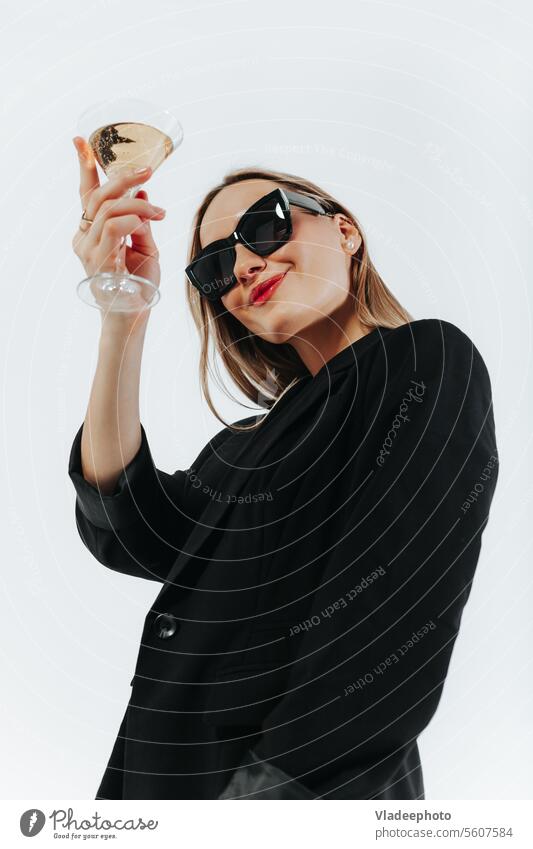 Woman in black look and sunglasses holds a glass of sparkling wine, cheering woman drink cheers alcohol wineglass white smiling alone female celebration holding