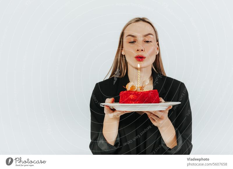 Blowing the birthday candles. Attractive young woman making a wish while holding a red cake blow celebrate attractive alone delicious blowing copy space party