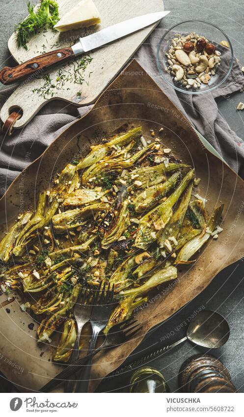 Delicious roasted fennel with nuts on baking sheet on kitchen table with utensils , top view delicious nutrition baked vegetarian grilled organic homemade food