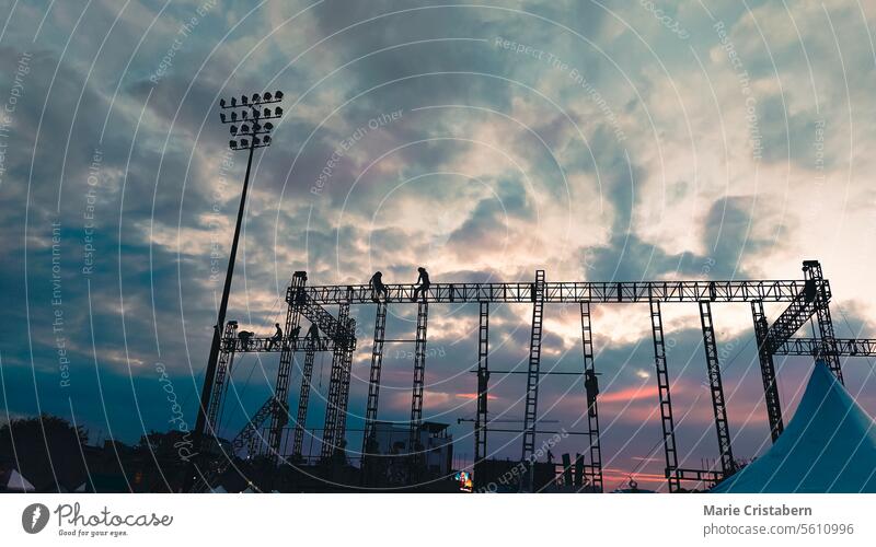 Stadium lights against a vivid dusk sky with colorful clouds stadium silhouettes vertical industry scaffolding construction power evening electrical