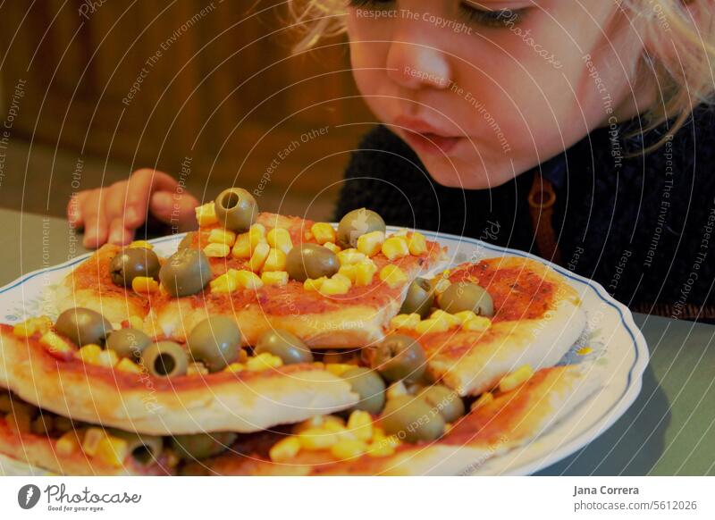 A child blows on freshly baked pizza Eating Pizza Child Fresh vegetarian vegan Dinner Self-made occupied Olive Maize pizza bread pizza dough hungry Hot