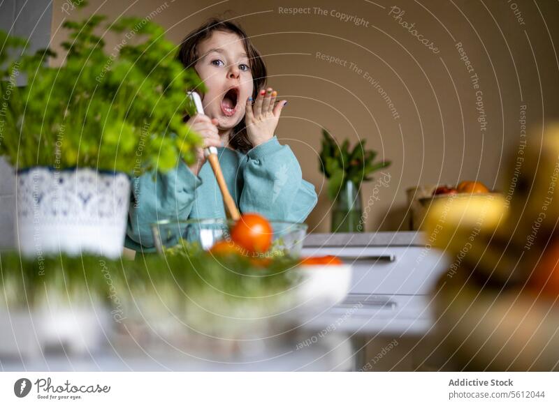 Socked female kid preparing salad at home girl portrait surprise cute caucasian open mouth selective focus person lifestyle leisure innocent casual attire shock