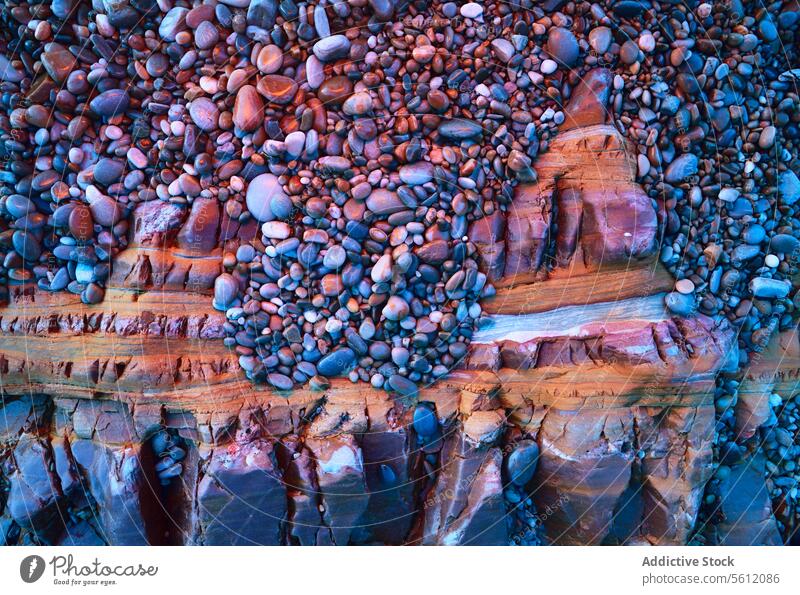 Pebbles on layered sedimentary rock formation pebble natural texture stone geology mineral earth pattern coastline shore colorful vibrant geological erosion