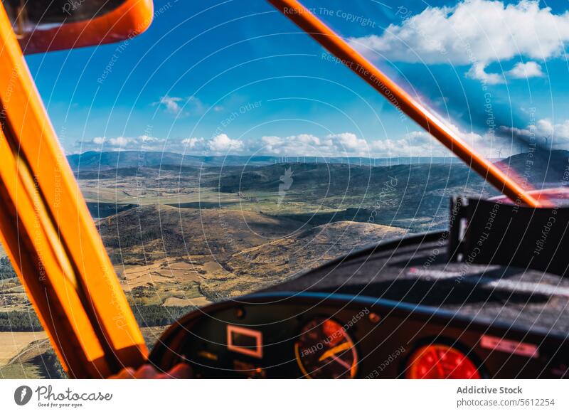Cockpit View from an aircraft of an expansive landscape on a cloudy day cockpit view vintage plane blue sky instrument panel orange structure adventure flight