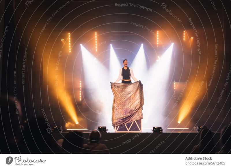 Magician performing disappearing trick on stage man magician show box fabric illusion male illusionist performer conjurer hall audience mystery smoke spotlight