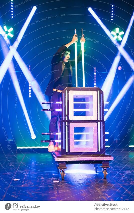 Magician performing trick on stage man magician show illusion box fantasy male performer illusionist conjurer swords festive glow event effect illuminate