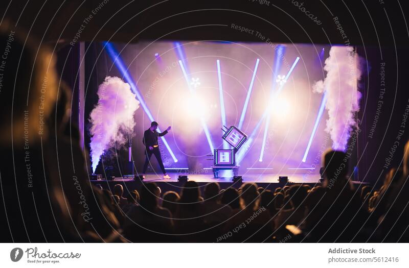 Crowd of people watching magical performance on stage magician show trick smoke illuminate audience male illusionist conjurer performer box glow fume entertain