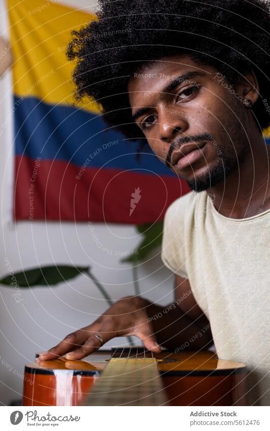 Man in casuals playing guitar at home man young focus acoustic string instrument colombian flag weekend closeup headshot music talent hobby entertain guitarist