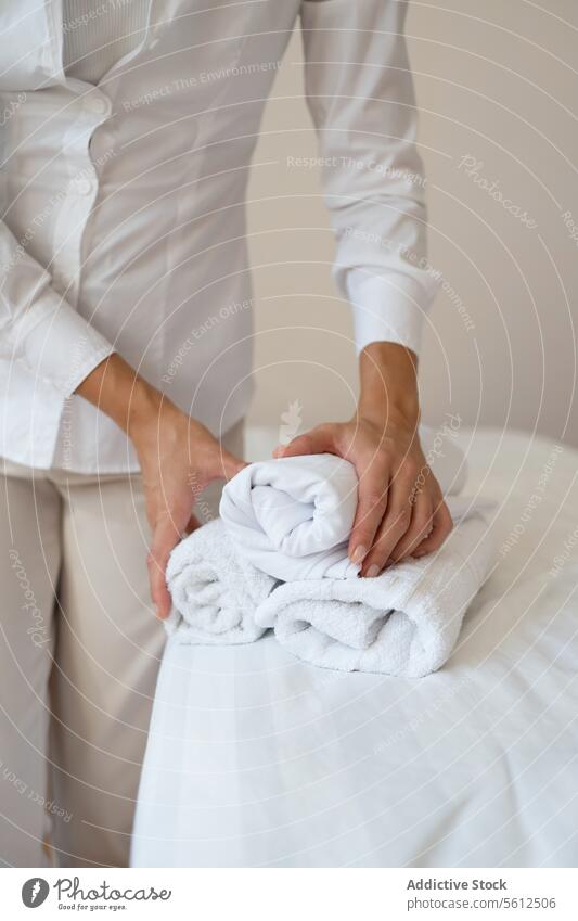 Crop hand of anonymous female massage therapist in white uniform standing and holding clean rolled up towels while working in spa salon crop woman cotton fabric