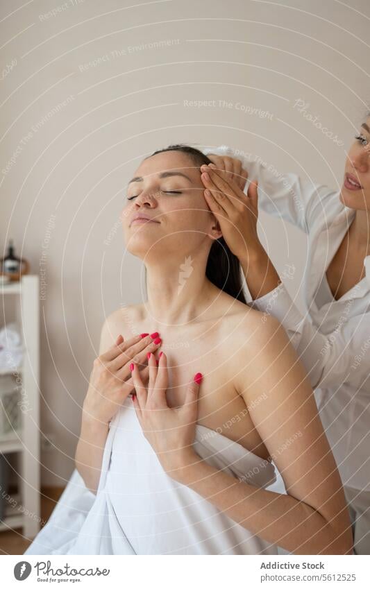 Crop hands of unrecognizable masseuse doing hair massage to topless female customer enjoying therapy with closed eyes in spa session head eyes closed crop sit
