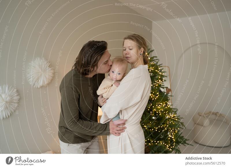 Family moment with baby during holiday season family christmas love tender parents affection tree lights festive together home happy care embrace celebration