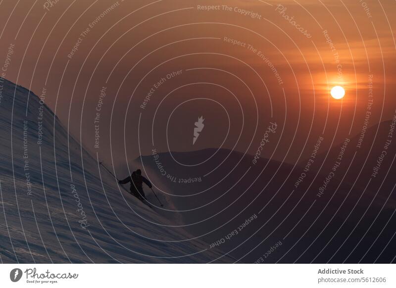 Skier skiing on Japanese alps slope at sunset skier person silhouette mountain range active highland top beautiful view shine sky snowcapped japan danger pole