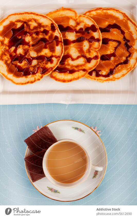 Breakfast with coffee and stacked waffles on blue breakfast syrup cup saucer milk background overhead view drizzle morning meal food refreshment table snack