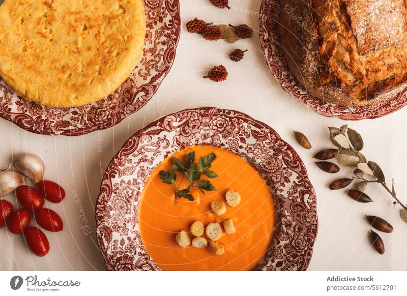 Tasty spanish omelette and a creamy salmorejo soup wit croutons and bread on decorative plates. autumn pumpkin table cozy garnish seed food meal spread autumnal