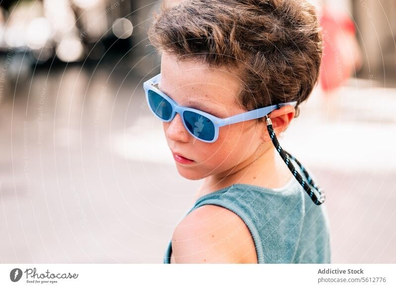 Calm boy in goggles looking away cute sunglasses face blurred background closeup serious tank top blue attractive calm serene lifestyle fashion trendy confident