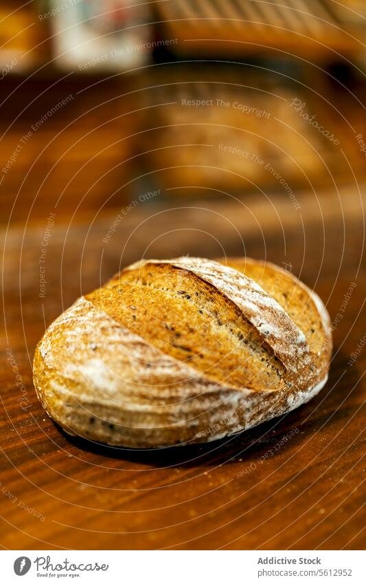Closeup of freshly baked tasty loaf of bread with crispy crust placed on wooden table in kitchen at bakehouse closeup whole wheat healthy organic flour
