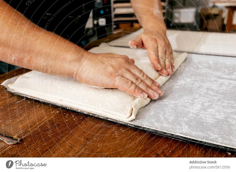 Baker making delicious pastry in kitchen chef dough stuffing table wooden bakery sieve food fresh tasty craft casual attire bakehouse man cooking focus