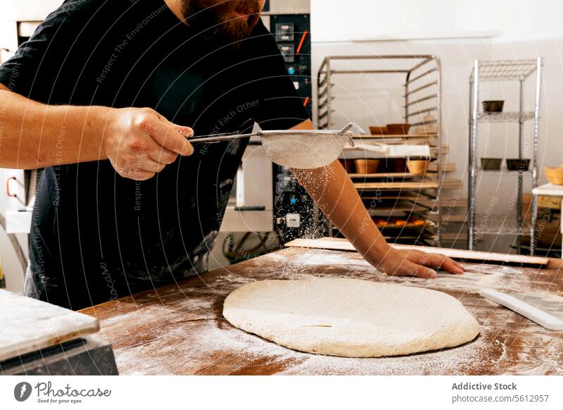 Crop man sifting flour on dough at table chef crop baker wooden pastry making kitchen bakery sprinkle bread ingredient knead prepare raw hand body part