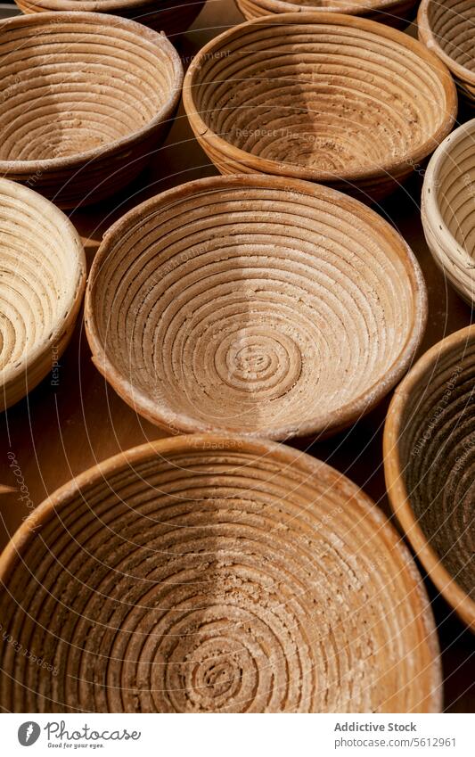 Closeup of round wooden bowls in bakery basket proofing mold brown circle shape kitchen bakehouse high angle container utensil arranged table closeup still life