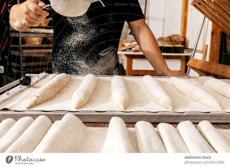 Crop man sifting flour on raw bread in bakery loaf dough tray crop hand facelift casual attire holding sieve making kitchen chef pastry sprinkle ingredient