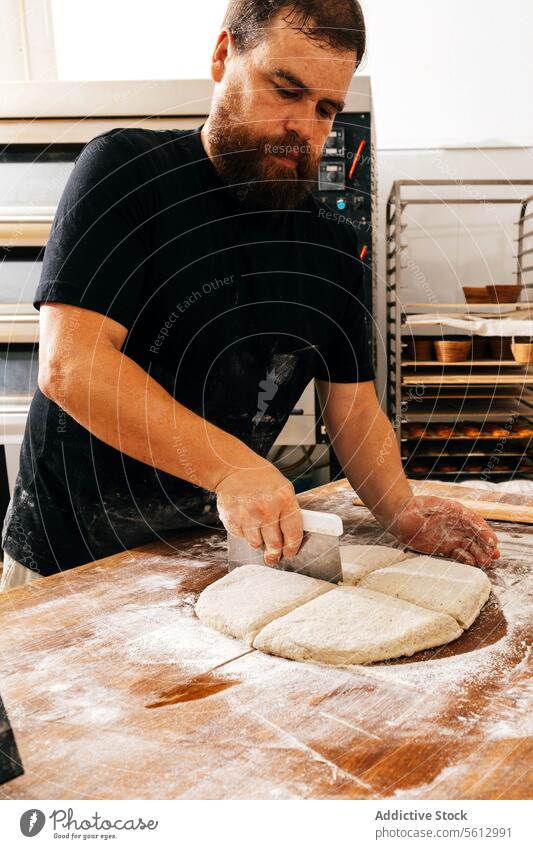 Make chef cutting fresh dough in bakery cook man flour cutter scraper focus serious beard casual attire wooden table concentrate prepare pastry kitchen food