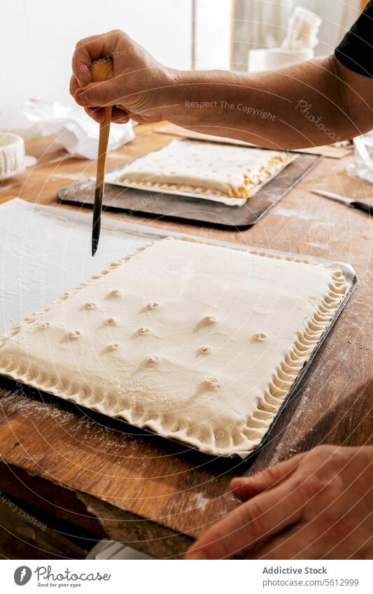 Chef preparing stuffed pastries in bakery pastry dough hole tool crop hand chef cook tasty wooden table tray holding bakehouse unrecognizable making delicious