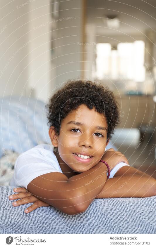 Happy boy resting on couch at home portrait smiling closeup sofa leaning living room looking happy black comfortable calm blurred background dark hair lifestyle