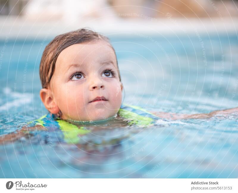 Closeup of little boy with inflatable jacket in swimming pool while enjoying vacation during summer cute playing floating water playful child safety active