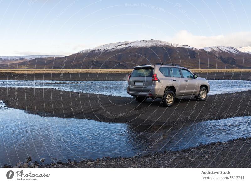 Gray SUV crossing a river in Iceland's Thorsmork valley against snowy mountains iceland thorsmork highland suv all-wheel drive vehicle river crossing outdoor
